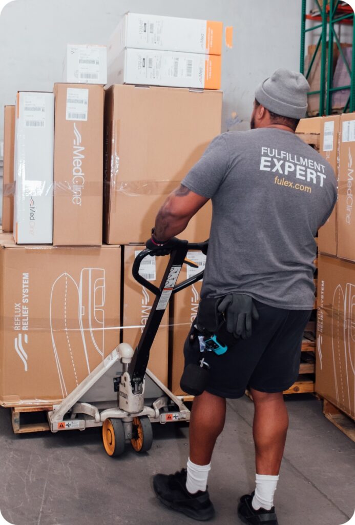 man with a pallet jack pulling a pallet of boxes